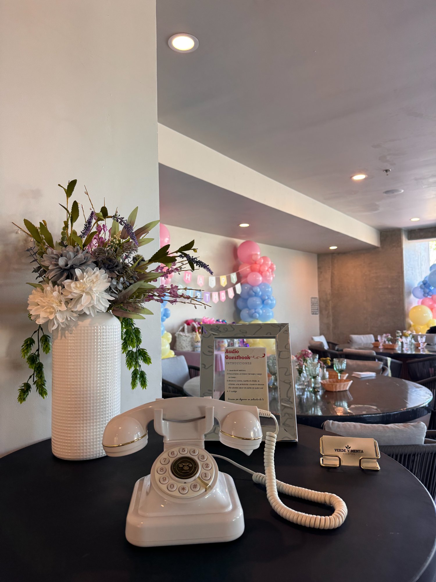 Audio Guest Book de Verde y Menta Eventos — teléfono retro blanco con flores y globos de colores en fiesta