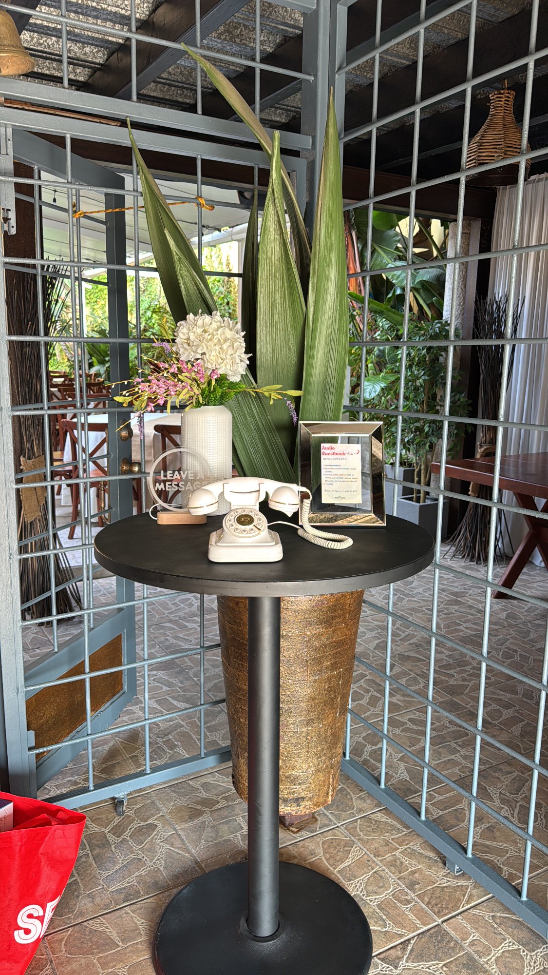 Audio Guest Book con teléfono retro blanco sobre mesa en restaurante con plantas tropicales
